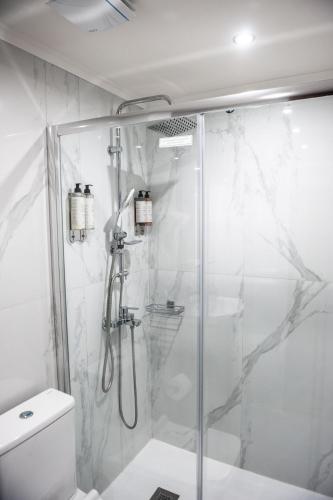 a white bathroom with a shower and a toilet at SeaFront Stone Suites in Vonitsa