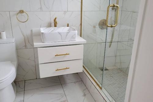 a white bathroom with a sink and a shower at Jamrock Place in Montego Bay