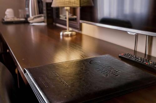 a book on a desk with a remote control at Best Western Plus Atakent Park Hotel in Almaty