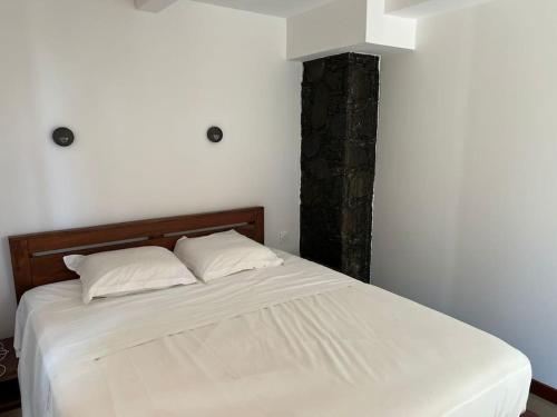 a bedroom with a bed with white sheets and pillows at Appartement Jacuzzi - Tec-Tec 1 in Trois Bassins