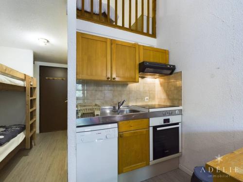 une petite cuisine avec un évier et une cuisinière dans l'établissement Studio mezzanine rénové 26m², au pied des pistes, balcon, 4 pers, proche commerces et garderie - FR-1-398-497, à La Rosière