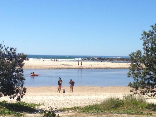 a group of people standing on a beach at White Waves on the Beach in Hastings Point