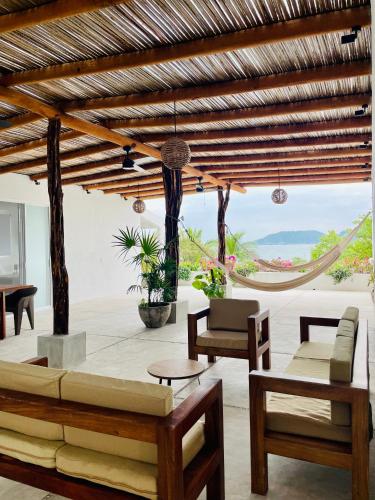 a living room with a couch and chairs and a hammock at Casa A la Mar in Zihuatanejo