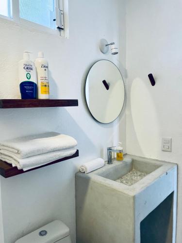 a bathroom with a sink and a mirror and a toilet at Casa A la Mar in Zihuatanejo