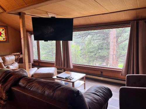a living room with a couch and a large window at Rose Den - Romantic Mountain Cabin with Views! in Estes Park