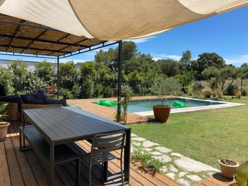 une terrasse en bois avec une table et une piscine dans l'établissement Villa familiale avec piscine, à Assas