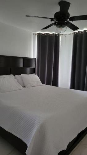 a bedroom with a white bed with a ceiling fan at Jamrock Place in Montego Bay