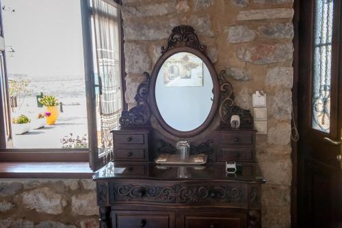 a bathroom with a sink and a mirror on a stone wall at SeaFront Stone Suites in Vonitsa
