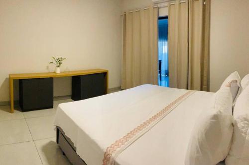 a bedroom with a large white bed and a desk at Localizaçao privilegiada centro in Delfinópolis