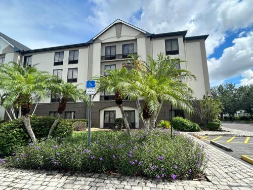 a building with palm trees and flowers in front of it at Red Roof PLUS Fort Myers in Fort Myers