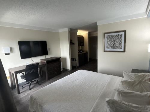 a hotel room with a bed and a desk and a television at Red Roof PLUS Fort Myers in Fort Myers