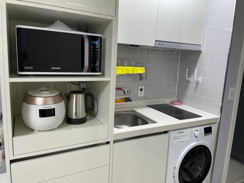 a small kitchen with a microwave and a sink at Yeosu U Bless in Yeosu