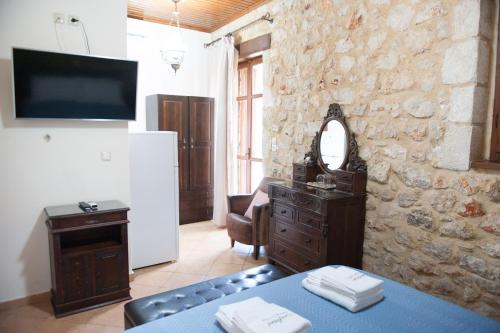 a living room with a table and a tv and a stone wall at SeaFront Stone Suites in Vonitsa