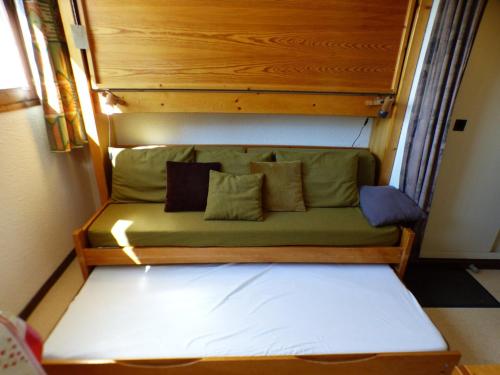 - un canapé vert avec des oreillers dans l'établissement Appartement studette cosy, centre Les Saisies, 2 pers. - FR-1-594-173, à Hauteluce