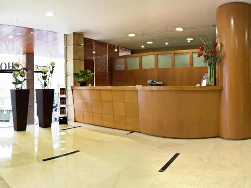 a lobby with a counter with flowers on it at Hotel Sercotel Tres Luces in Vigo