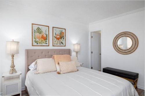 a white bedroom with a large white bed with two pillows at Beach Blessing - Oceanfront Pool Balcony in North Topsail Beach