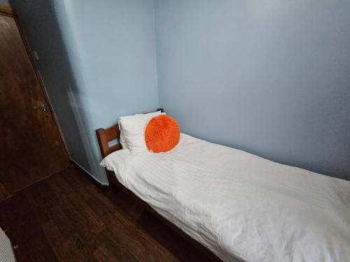 a small bed with an orange pillow on it at SnoozeDen Wellesley - Near to Slough Station in Slough