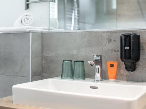 a bathroom sink with two cups and a soap dispenser at Apart33 Top 2-1 in Haus im Ennstal