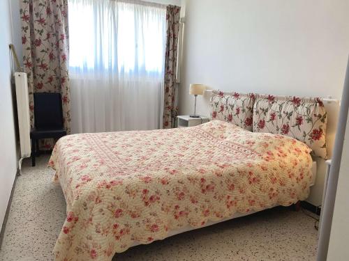 a bedroom with a bed with a flowered blanket and a window at Superbe T3 avec loggias fermées, garage, et wifi à Balaruc-les-Bains, classé 3 étoiles - FR-1-553-216 in Balaruc-les-Bains
