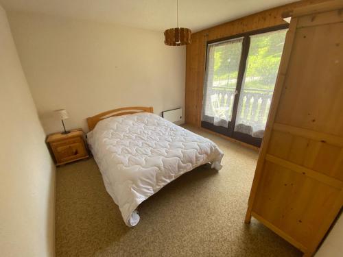 une chambre avec un lit blanc et une fenêtre dans l'établissement Appartement familial à 1 km du centre, proche télécabines et activités, multi Pass à 3€/jour - FR-1-693-99, à Châtel