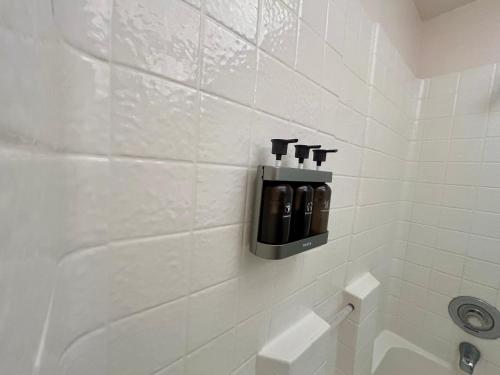 a white tiled bathroom with a soap dispenser on the wall at Starlight Western Room in Hemet