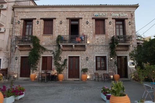 a woman sitting in front of a brick building at SeaFront Stone Suites in Vonitsa