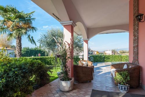 a porch with wicker chairs and a palm tree at B&B Villa Gloriana in Sona
