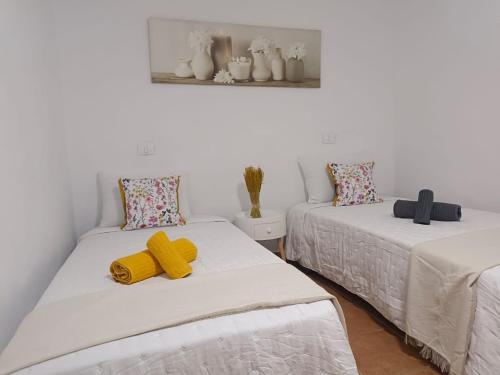Dos camas en una habitación con toallas amarillas. en Casa La Caracola, en El Golfo