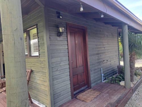 a wooden front door of a house with a porch at Waterfront luxury tiny house in Tairua