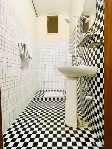 a bathroom with a sink and a black and white checkered floor at Airport Hotel Bed & Rest in Karachi