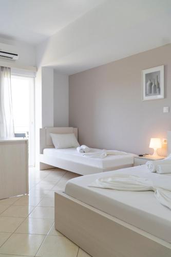 a white room with three beds and a window at Koks’ Guesthouse in Himare