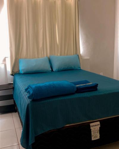 a bed with blue pillows and a blue blanket at Pousada Andrade in Parnaíba