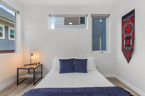 a white bed with blue pillows in a bedroom at Vermithor's Bronze Ember Sweet Suite in Seattle
