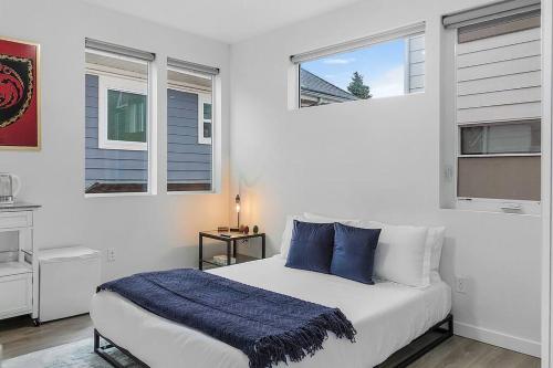 a bedroom with a bed with blue pillows and two windows at Vermithor's Bronze Ember Sweet Suite in Seattle
