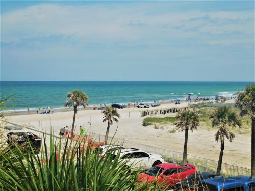 a beach with cars parked in front of the ocean at Beachside Bliss Ocean-View Condo with Pool and Private Beach Access Perfect for Families and Couples in Daytona Beach