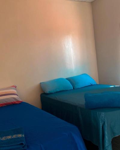 two beds in a room with blue pillows at Pousada Andrade in Parnaíba