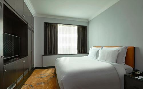 a bedroom with a large white bed and a television at Pullman Kuala Lumpur City Centre Hotel & Residences in Kuala Lumpur