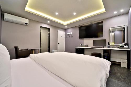 a hotel room with a white bed and a desk at Daegu Hotel Rubato in Daegu