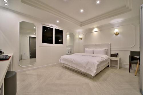 a white bedroom with a large bed and a desk at Daegu Hotel Rubato in Daegu