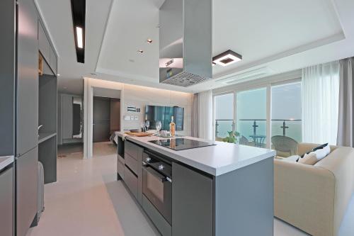 a kitchen and living room with a view of the ocean at Elmomento Songdo in Busan