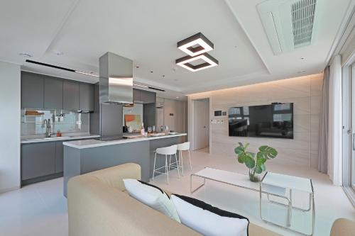 a living room with a couch and a kitchen at Elmomento Songdo in Busan