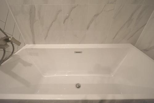 a white bath tub in a bathroom with marble walls at Daegu Hotel Rubato in Daegu