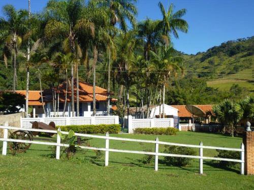 una recinzione bianca di fronte a una casa con palme di Casa Coronel Estevão a Santo Antônio do Jardim