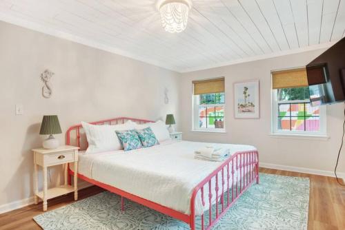 Un dormitorio con una cama y una mesa y dos ventanas. en Salt Gypsy Unit A Expansive Outdoor Space w Pool, en Tybee Island