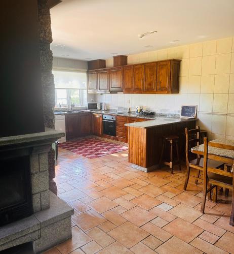 a kitchen with wooden cabinets and a table and a fireplace at The Oak´S Wolf-Country House in Fafe