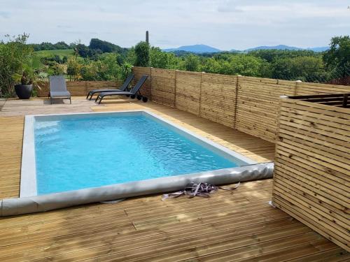 - une piscine sur une terrasse avec une clôture en bois dans l'établissement Grande maison avec piscine à Urt, proche de Bayonne - FR-1-239-653, à Urt