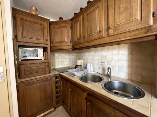 une cuisine avec des armoires en bois et un évier dans l'établissement Duplex 6 pers avec terrasse et parking privatif à Banyuls-sur-Mer - FR-1-309-82, à Banyuls-sur-Mer