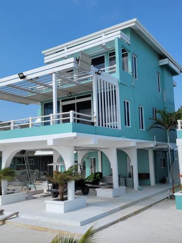 a blue house with a balcony on the beach at Island Magic Villas in Caye Caulker