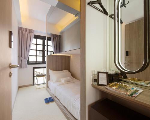 Un dormitorio pequeño con una cama y un espejo. en ST Signature Chinatown, en Singapur