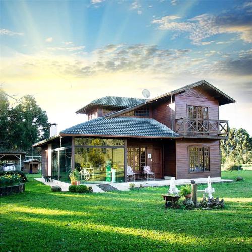 a house in a field with a green yard at Chalés Rota das Cachoeiras in Urupema
